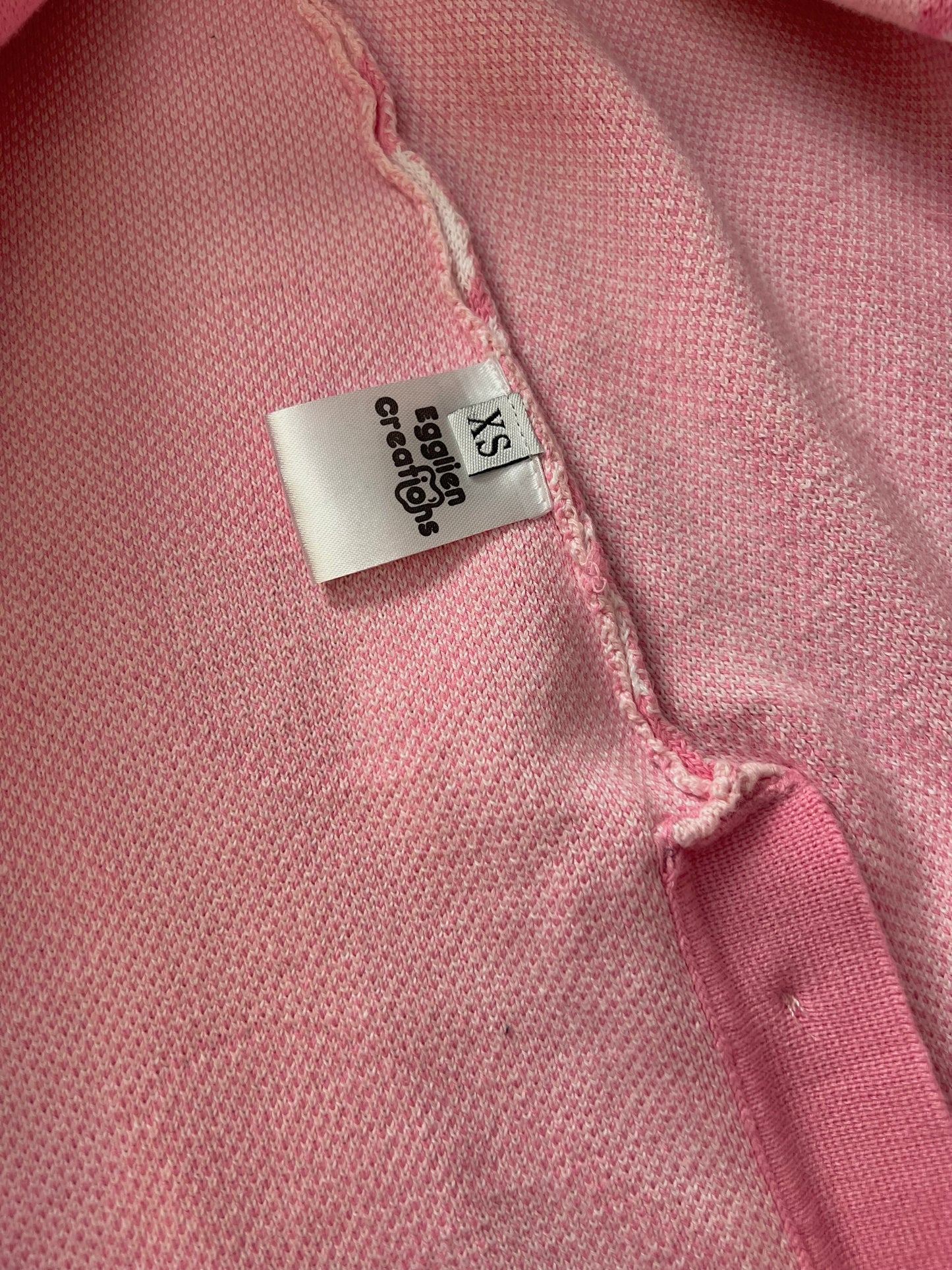 A close up image of the inside of the cardigan side seam. A Egglien Creations washing label and size XS label sewn into the seam.