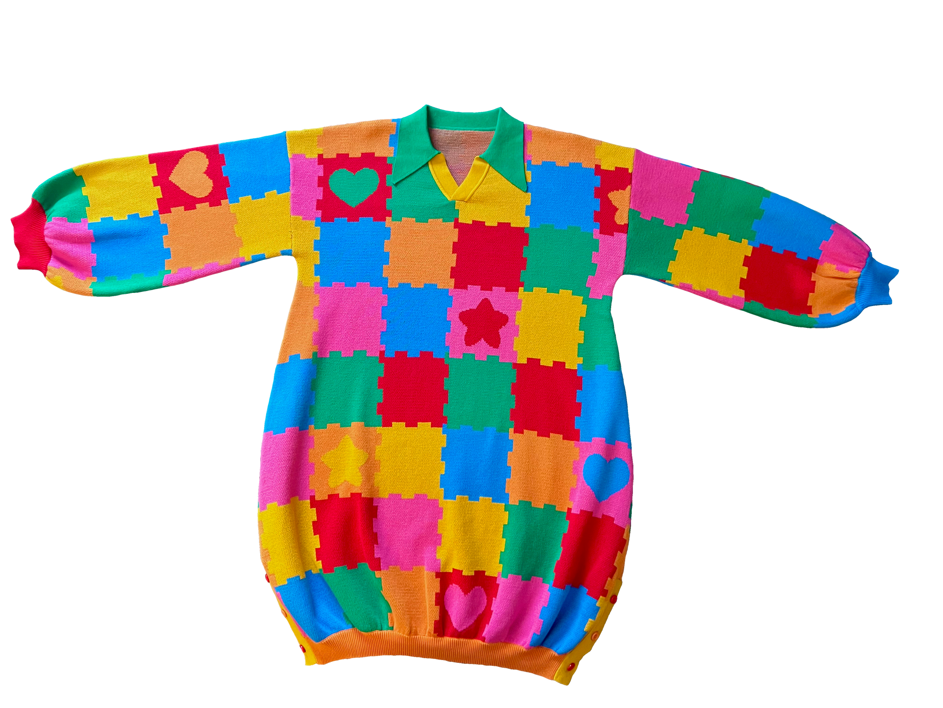 Flat lay of the front of the knit sweater dress with a green collar. The design is bright pink, red, yellow, green, and orange puzzle playmat tiles with some tiles having hearts or stars.