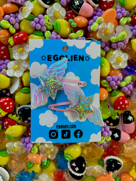 Egglien Holographic silver star and holographic white wings on a pink hairclip with a background of colorful resin pieces