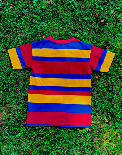 Red, yellow, blue striped shirt with mismatched stripes on the sleeves laying flat and face down on grass