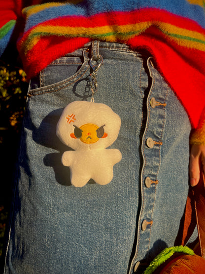 Plush egg keychain with angry expression hanging on a girl wearing aJean skirt and a rainbow sweater