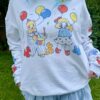 Woman wearing a white sweatshirt with colorful clown design and a jean skirt outdoors.