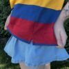 Girl wearing a red, yellow and blue shirt outdoors showing the side seam and slit of the shirt
