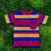 Red, yellow, blue striped shirt with mismatched stripes on the sleeves and pocket laying flat on grass