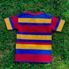 Red, yellow, blue striped shirt with mismatched stripes on the sleeves laying flat and face down on grass