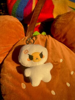 Plush egg keychain with angry expression on a brown burger bag