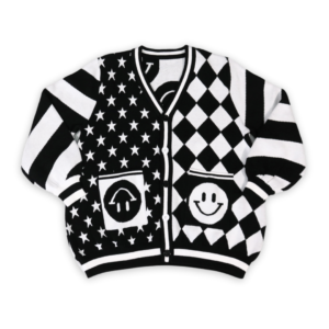 Flat lay of the front of a black and white mismatched pattern cardigan. Sleeves have diagonal stripes. Left panel has diagonal diamond pattern, the right has white stars on a black background with happy face pockets.