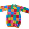 Flat lay of the front of the knit sweater dress with a green collar. The design is bright pink, red, yellow, green, and orange puzzle playmat tiles with some tiles having hearts or stars.