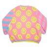 Pastel multicolored knit cardigan flayed flat with the back side facing the camera. Cardigan has multicolored stripe sleeves and yellow happy faces on a pink background body panel