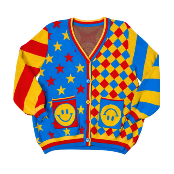 Bright red, yellow and blue cardigan laying flat with the front of the cardigan facing the camera. Cardigan has alternating color star patterns, checkered diamond patterns, alternating stripe sleeves and happy face pockets.