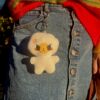 Plush egg keychain with angry expression hanging on a girl wearing a jean skirt and a rainbow sweater