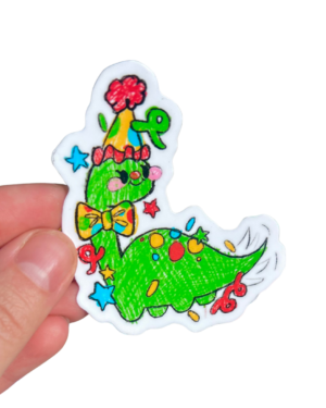 Hand holding a sticker of a Green dinosaur on a clear background. Green Dinosaur is wearing a party hat on its head and a colorful bow tie.