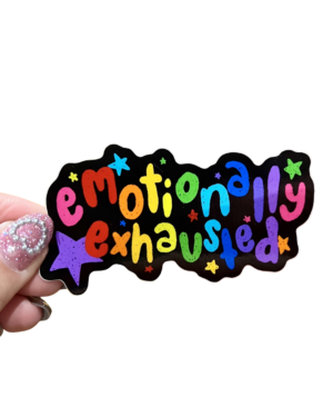 A sticker with the phrase 'emotionally exhausted' written in a colorful, playful font, held between fingers