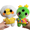 Two hands holding two different plush in each hand facing the camera. Hand on the right is holding a cheerful alien plushie wearing a rainbow cardigan. And the hand on the left is holding an mischievous alien plush wearing a yellow and orange cardigan.
