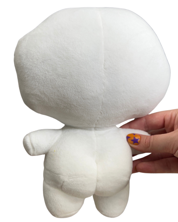 Hand holding a medium sized white plush with its back facing the camera. The white plush features a round head a small body and two round butt cheeks.