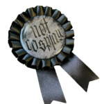 Black rosette pins with the text 'Not Cosplay' in black and white on a clear background