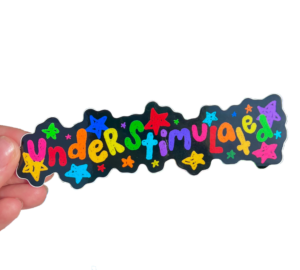 hand holding a sticker on a clear background. The sticker has a black background with playful rainbow stars and "Understimulated" on it