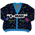 A multicolored cardigan laying flat with the front facing the camera with the text "***B-GRADE*** displayed in the center. The cardigan is bright pink,. purple, yellow, green and blue stars, circles, triangles, squares and confetti on a black background.