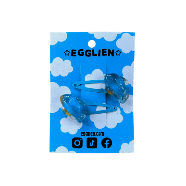 A pair of blue fish resin cabochon on blue hairclips both on blue backing card that reads "Egglien" and "egglien.com"