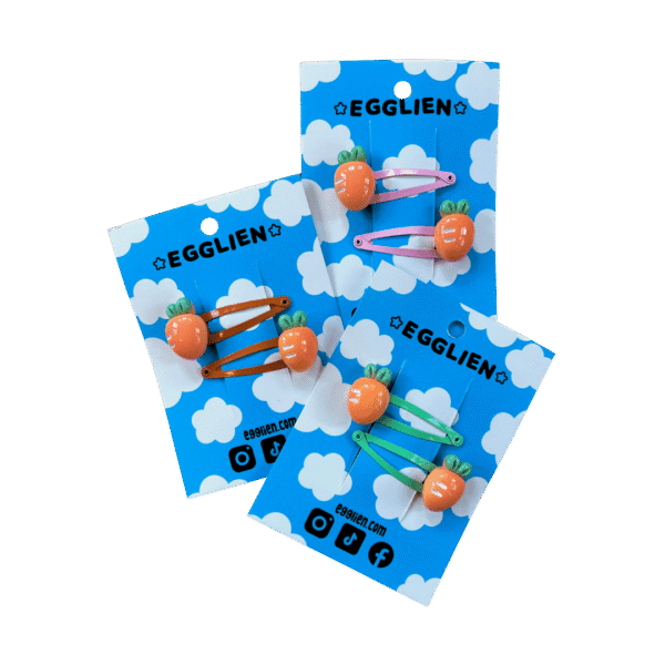 Three sets of carrot hairclips each on a blue backing card that reads "Egglien". One pair has pink hair clips, one has orange hair clips and one has mint hair clips.
