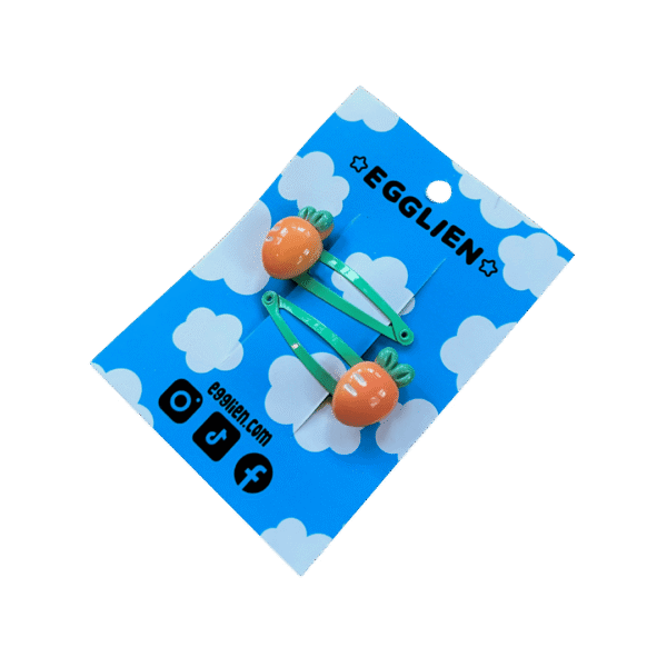 A pair of orange carrot cabochons on mint hairclips both on backing card that reads "Egglien"