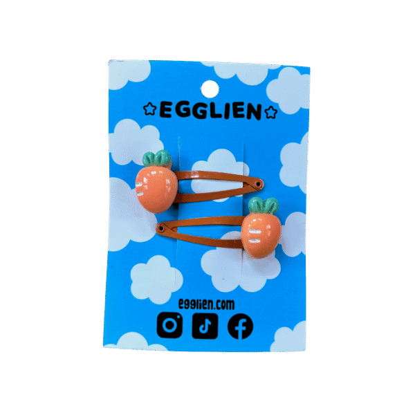 A pair of orange carrot cabochons on orange hairclips both on backing card that reads "Egglien"