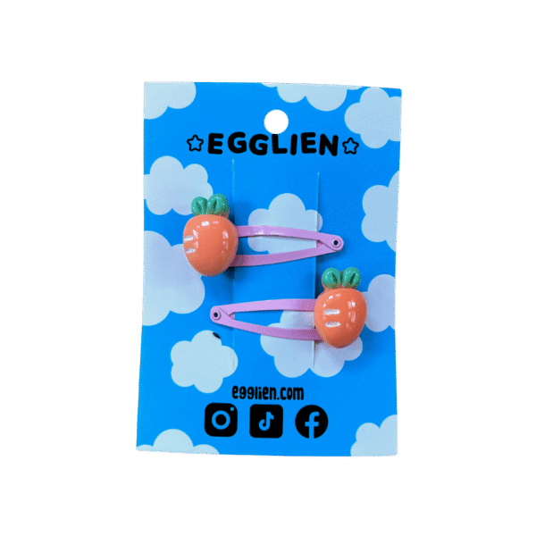 A pair of orange carrot cabochons on pink hairclips both on backing card that reads "Egglien"