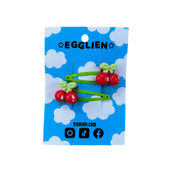 A pair of red cherry cabochons on green hairclips both on backing card that reads "Egglien"