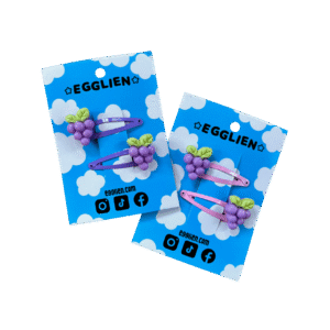 Two pairs of grape hairclips both on a blue backing card that reads "Egglien". One pair has yellow hair clips and one has orange hair clips.