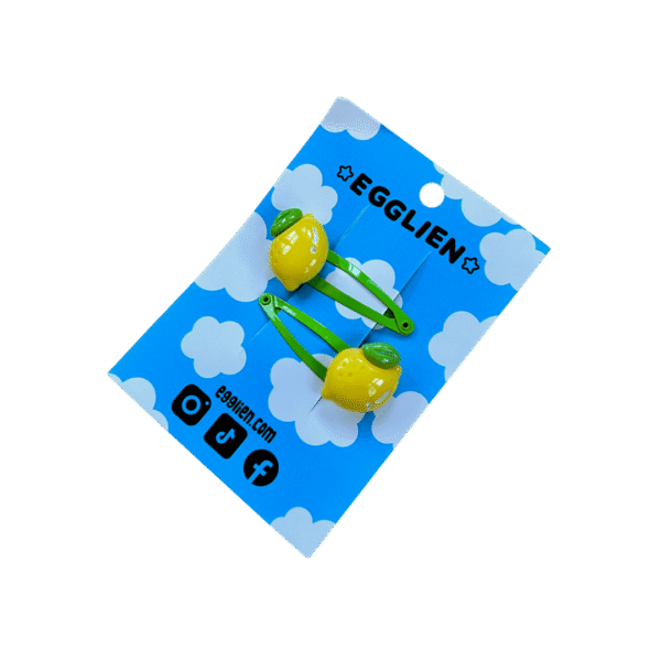 A pair of lemon resin cabochon on green hairclips both on backing card that reads "Egglien"