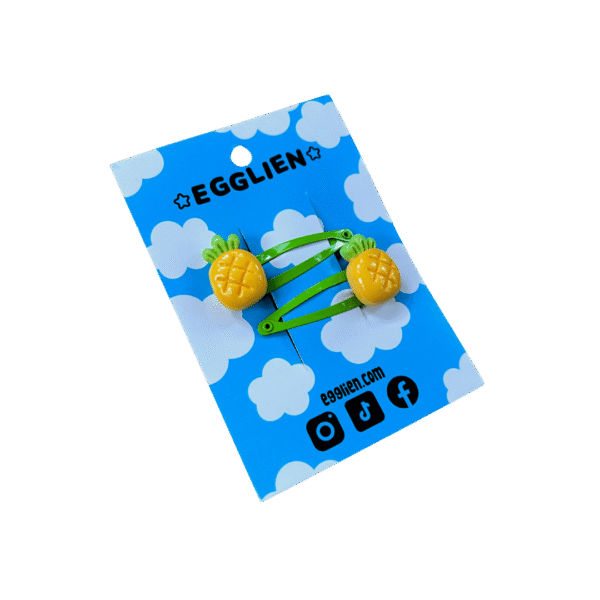 A pair of pineapple cabochons on green hairclips both on blue backing card that reads "Egglien"