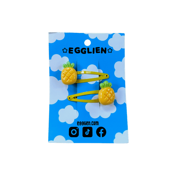 A pair of pineapple cabochons on yellow hairclips both on blue backing card that reads "Egglien"