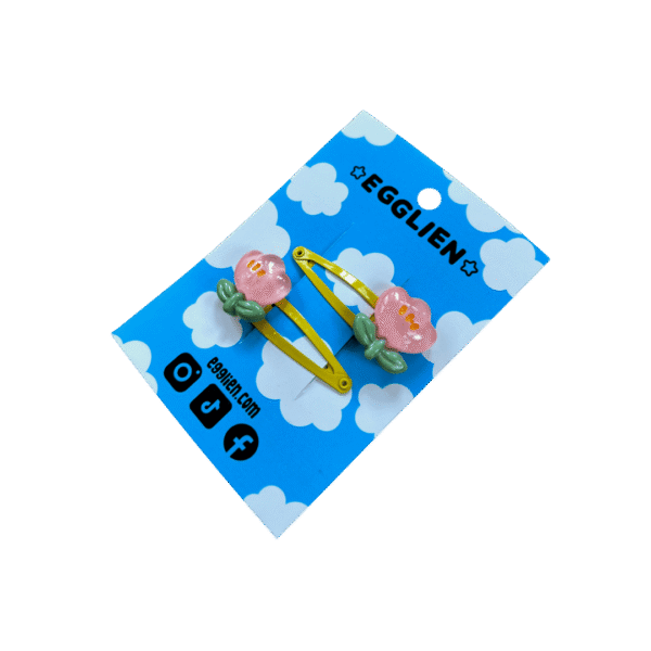 A pair of pink flower cabochons on yellow hairclips both on blue backing card that reads "Egglien"