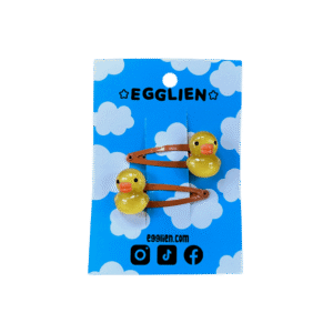 A pair of rubber duck cabochons on orange hairclips both on blue backing card that reads "Egglien"