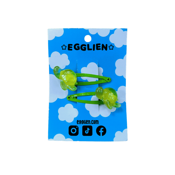 A pair of green turtle resin cabochon on green hairclips both on backing card that reads "Egglien" and "egglien.com"