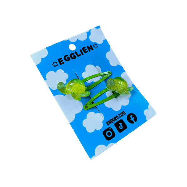 A pair of green turtle resin cabochon on green hairclips both on backing card that reads "Egglien" and "egglien.com"