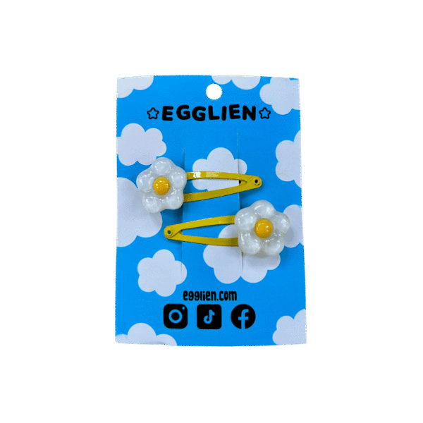 A pair of white and yellow flower resin cabochon on yellow hairclips both on backing card that reads "Egglien"