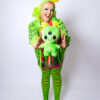 Girl playfully holding a cheerful alien plush toward the camera. She is wearing a matching alien green fuzzy headband with star antennae, a green slime cardigan, green and black striped tights and black mary janes
