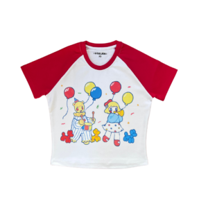 A white crop top with red short sleeves laying flat on a clear background. The shirt has a white body with playful primary colored clown characters, balloons and confetti printed on it.